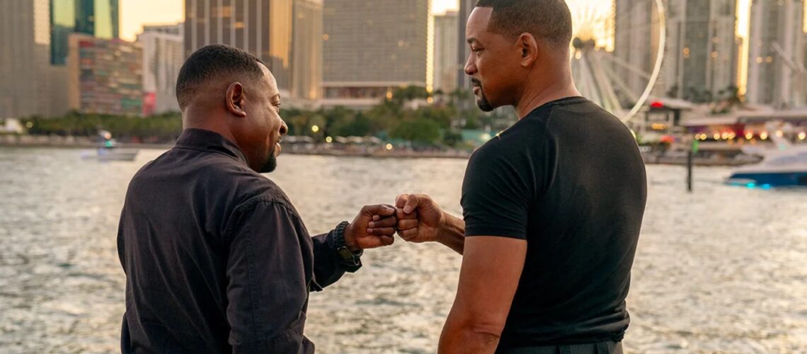 Mike and Marcus dap each other up in front of the water