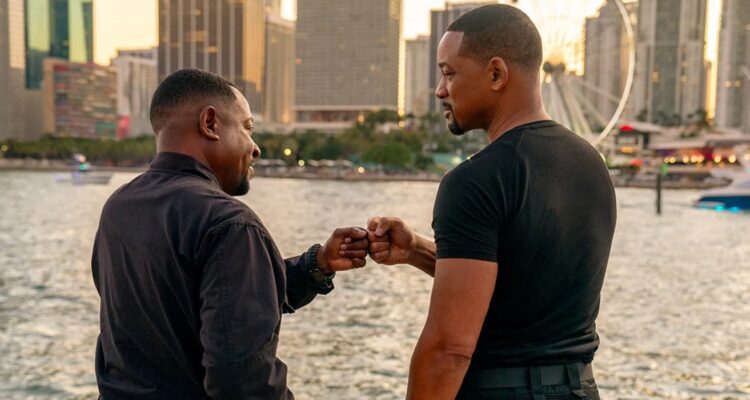 Mike and Marcus dap each other up in front of the water